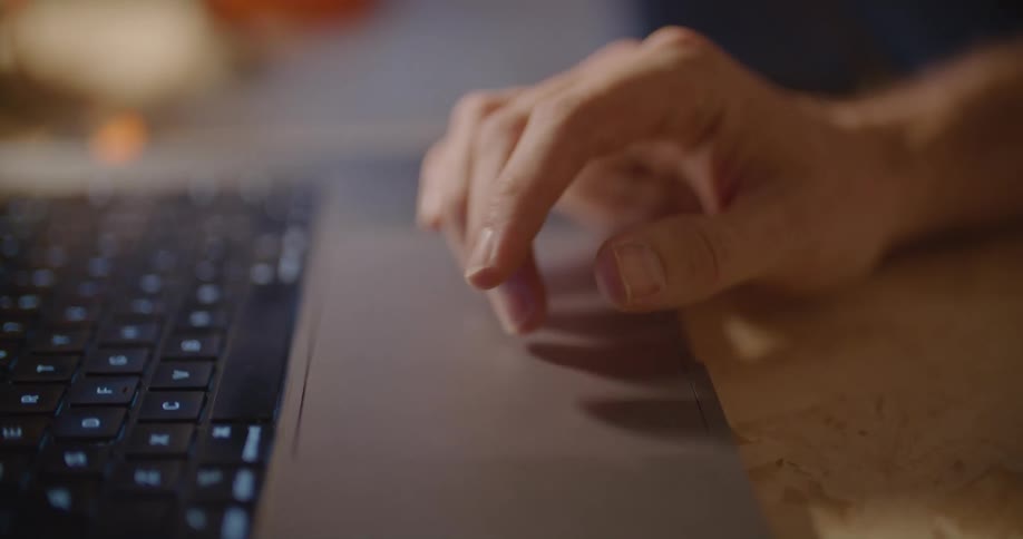 A hand and fingers move across the touch pad of a laptop computer