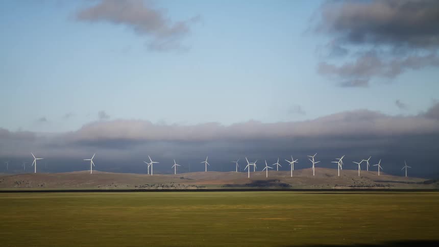 Wind turbines spin on a wind farm in the countryside during the day
