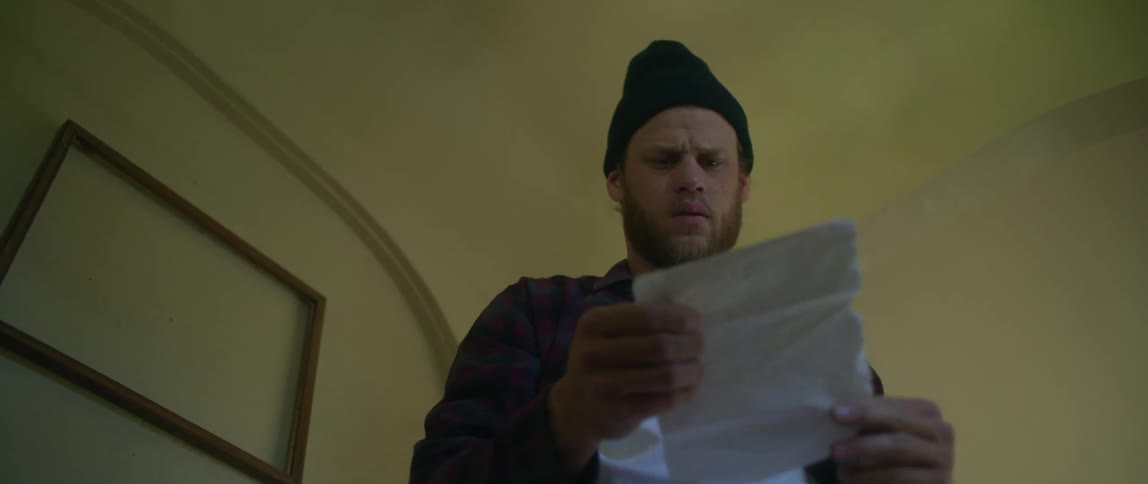 A man is reading a letter and then leaves the room
