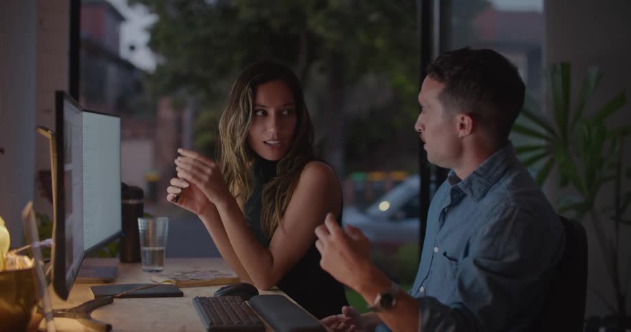 Man and woman are talking together while sitting at a computer desk