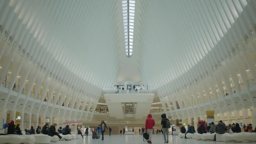 People walking through the world trade center transportation hub with some resting on benches