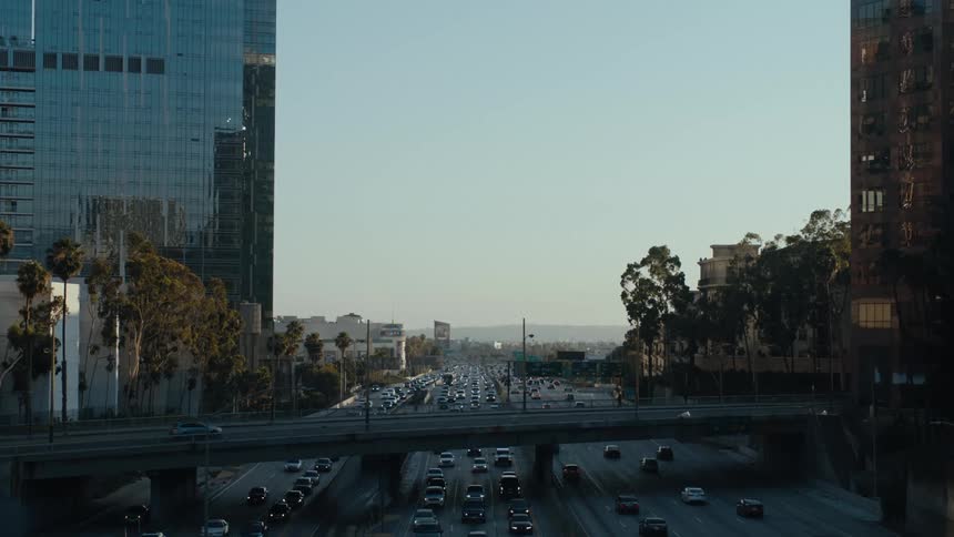 Cars cross busy highway during rush hour as mist covers mountains on the horizon