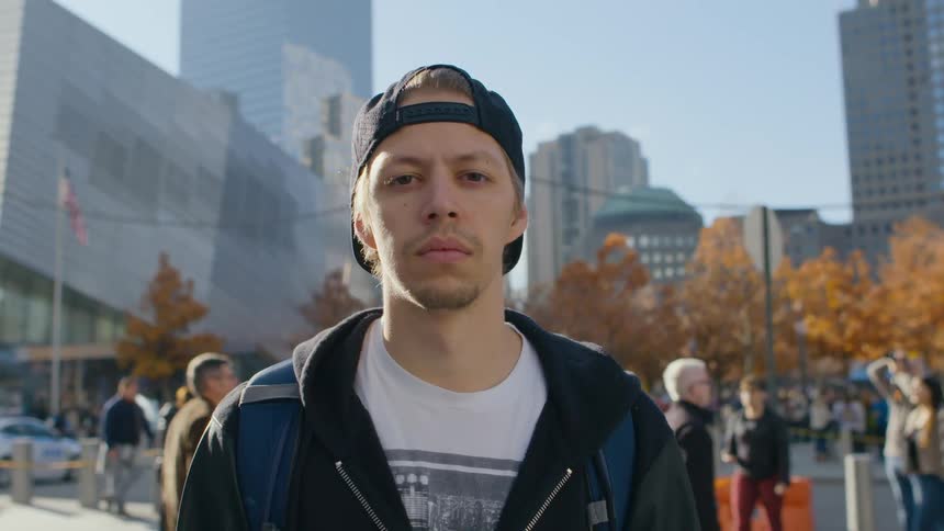 A man stands in a city as many people walk past him