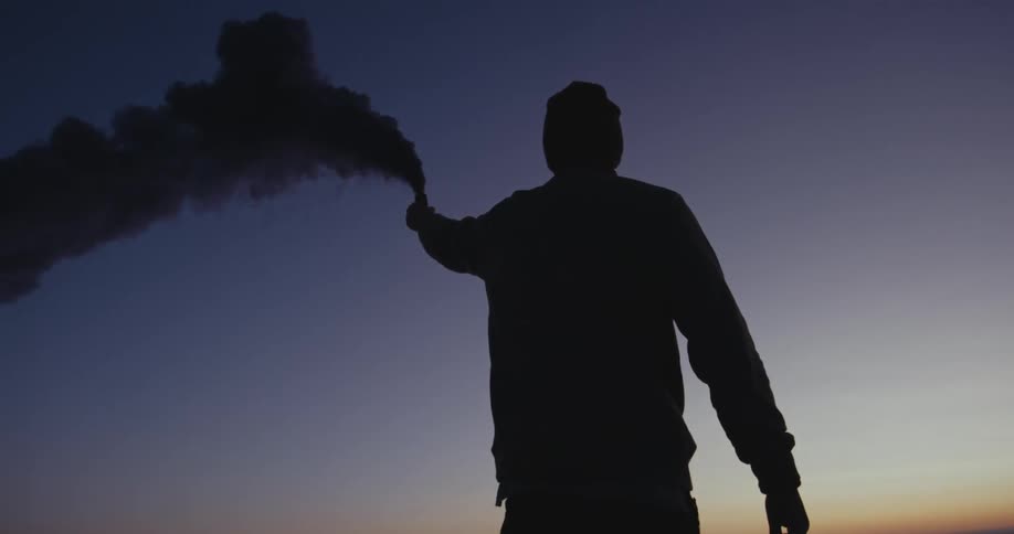 Spray can releases colored smoke into the air outdoors at night