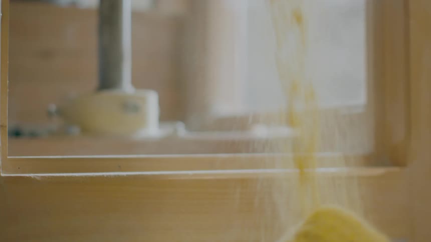 A grain mill rotates while distillers rains exit into a loaded bin.