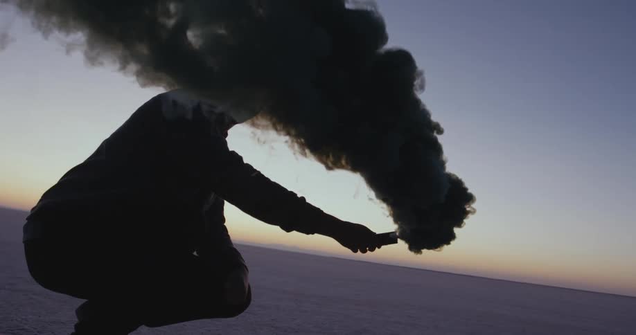 A man is holding fireworks outdoors at dusk