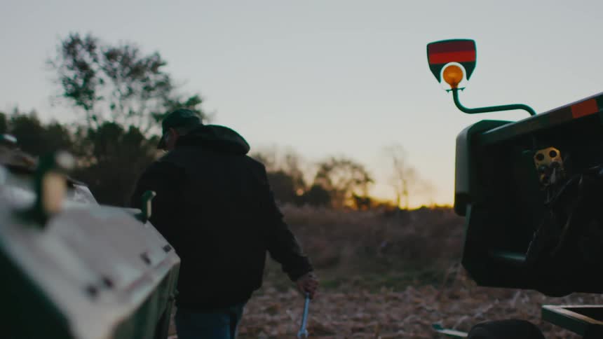 A man is walking around a farm near tractors