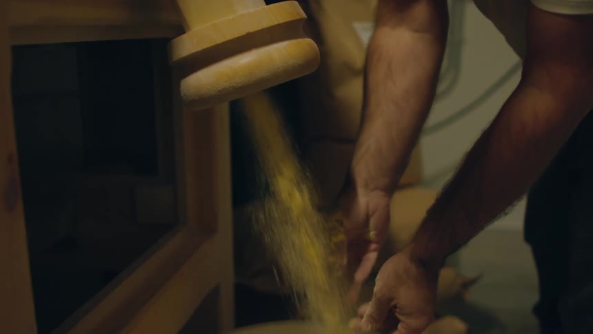 A person checking grain coming out of a chute