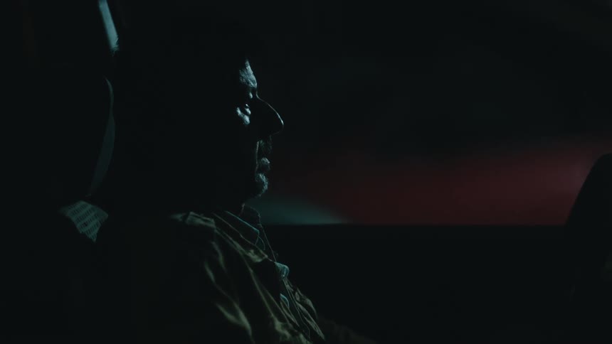 Man sits inside of a vehicle at night