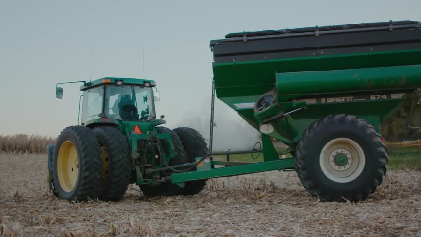 A person is driving a tractor through farm fields