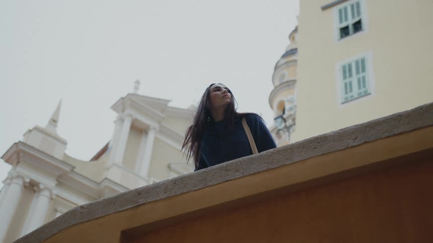 A woman is looking over the ledge in a city