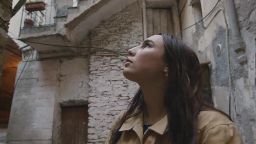 A woman looking up at old buildings in an old city