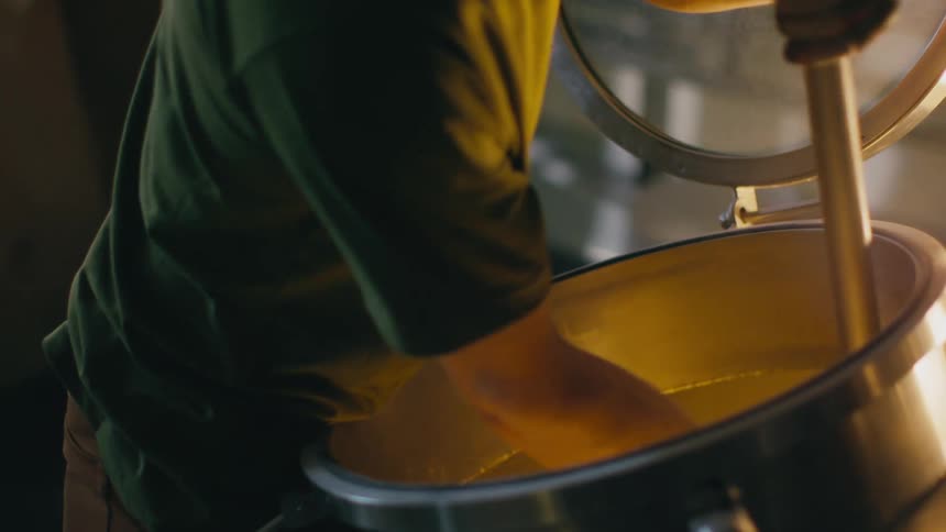 An employee stirring a vat of liquid