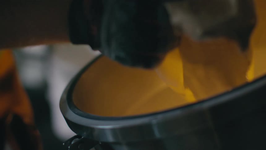 A person is pouring a bag into a distiller