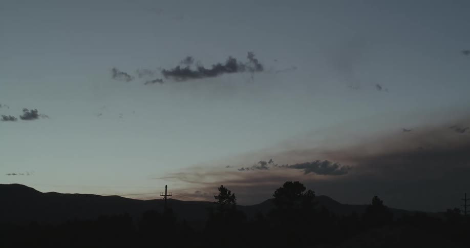 Mountain range sits behind the hydro poles at dusk