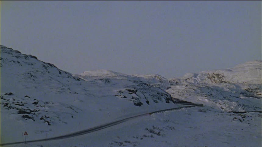 The hills around the road are covered with snow