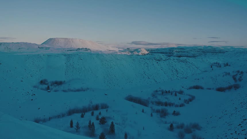 The sun sets over a snow covered mountain and field