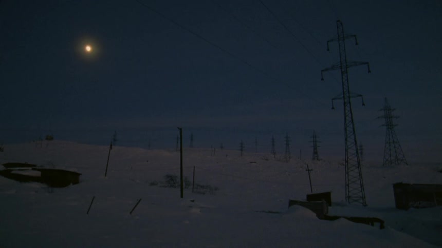 Power lines and electrical towers on a snow covered slope at night