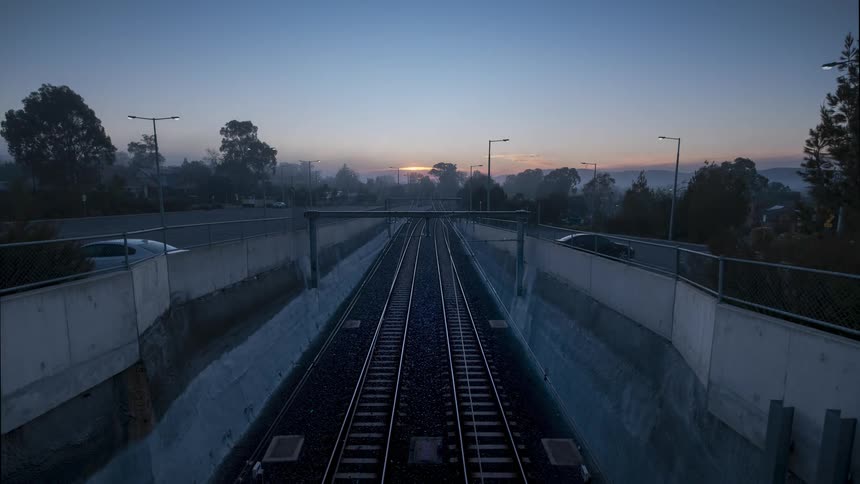 Trains travel on the railway as the sun rises on the horizon