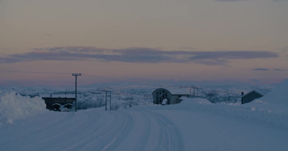 Tire tracks run down a snow covered road past rural homes
