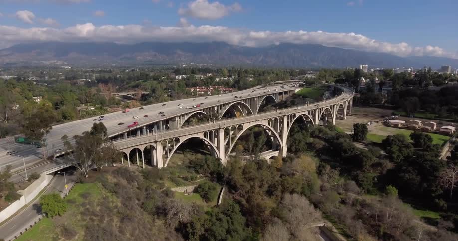 A highway below has cars traveling fast with a forest below
