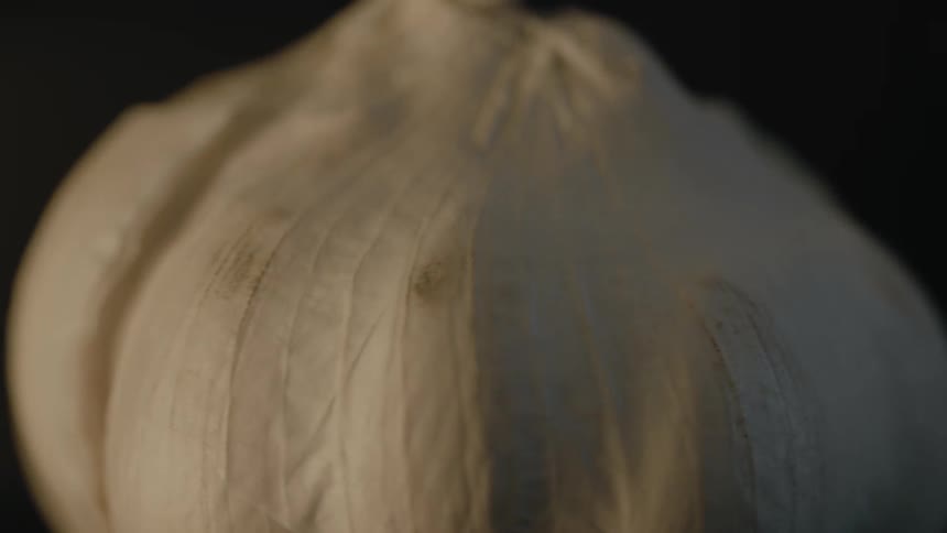 An unwashed clove of garlic spinning in a dark place