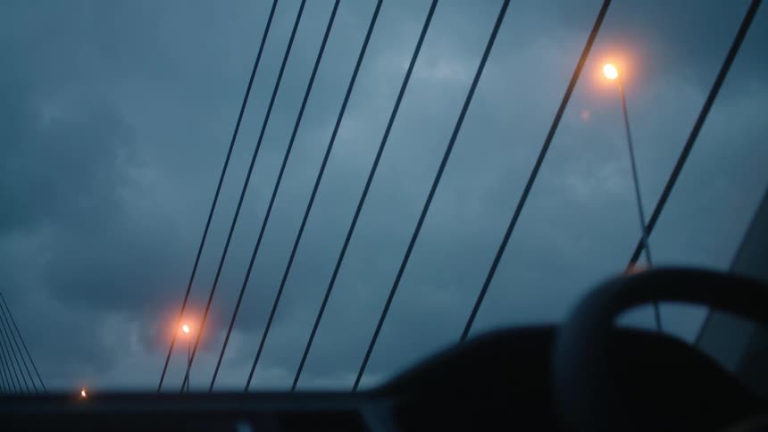 Car crosses bridge under lit streetlights passing the suspension cables