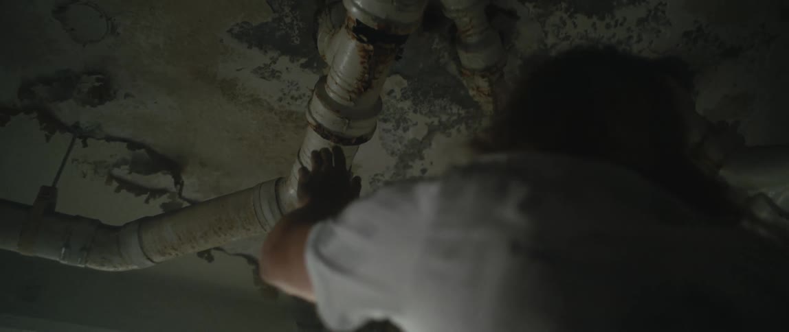A man checks a leaky pipe in his basement