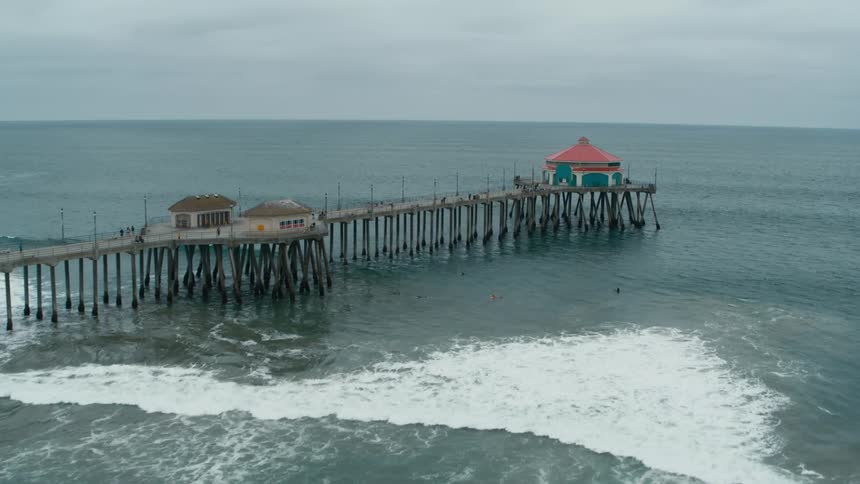 Aerial view of people on a beach close to the buildings over a pier in the coast