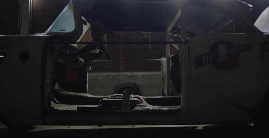 Vintage dismantled white car parked inside a dimly lit warehouse