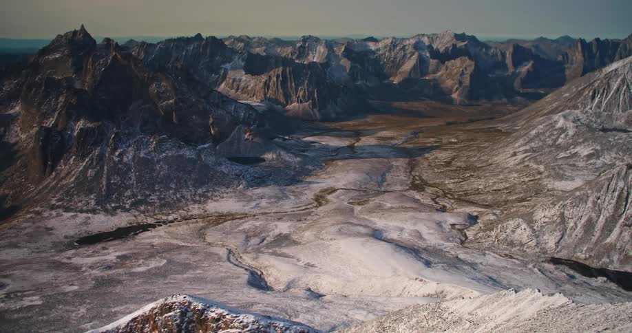 A barren valley in a mountain range during the day