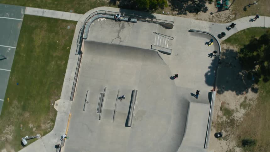 Skateboarders skate around a skate park during the day