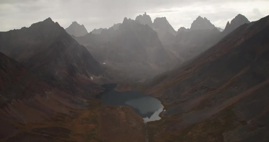 A smooth crater lake between the jagged mountain slopes and ridges