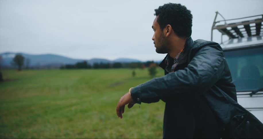 A man sits on his vehicle in a field