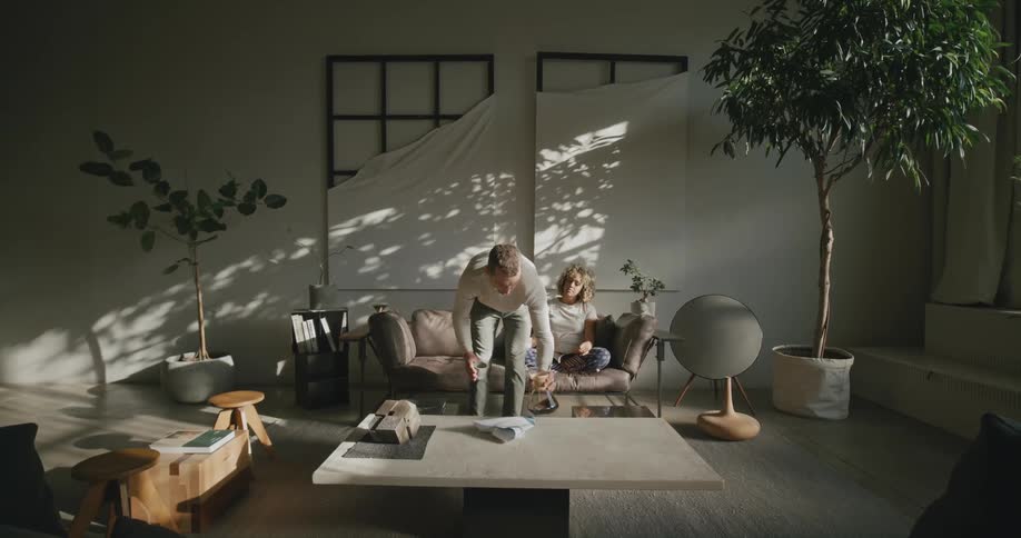 A man walks over to the couch with a drink
