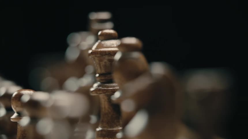 Carved stone chess pieces sit in rows in dark area