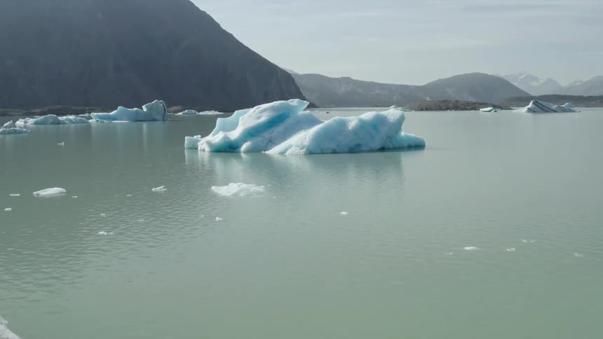 Large chunks of ice and ice bergs with streaks of black carbon on a lake