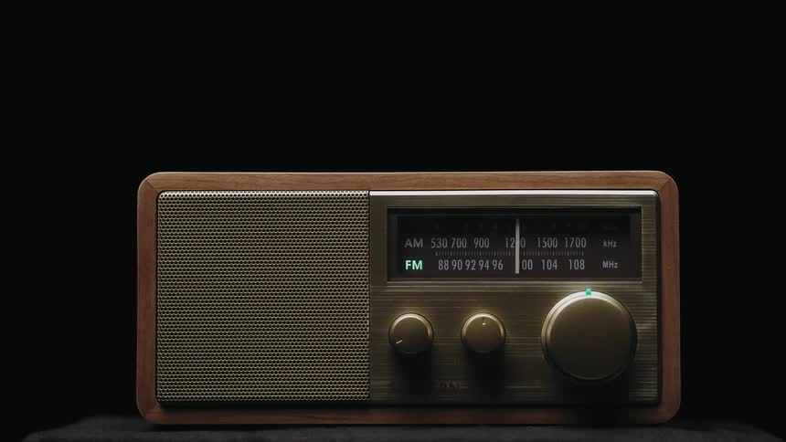 A hand turns a dial on a vintage radio to select an fm station