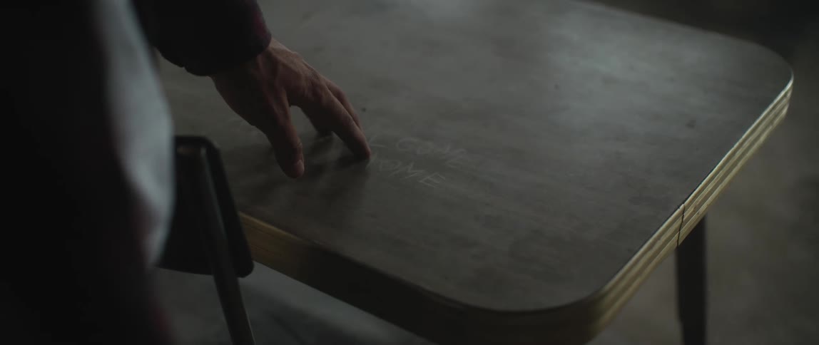 A man runs his fingers along the top of a desk