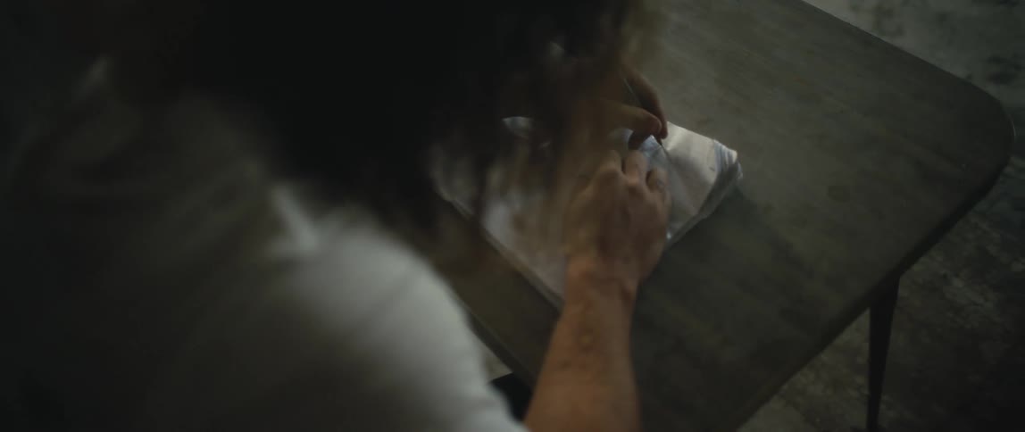 Man sits at small table writing in midsized notebook