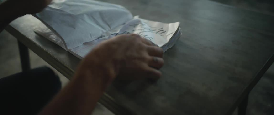 Man nervously turning the crumpled pages of a notebook filled with scribbles over a table