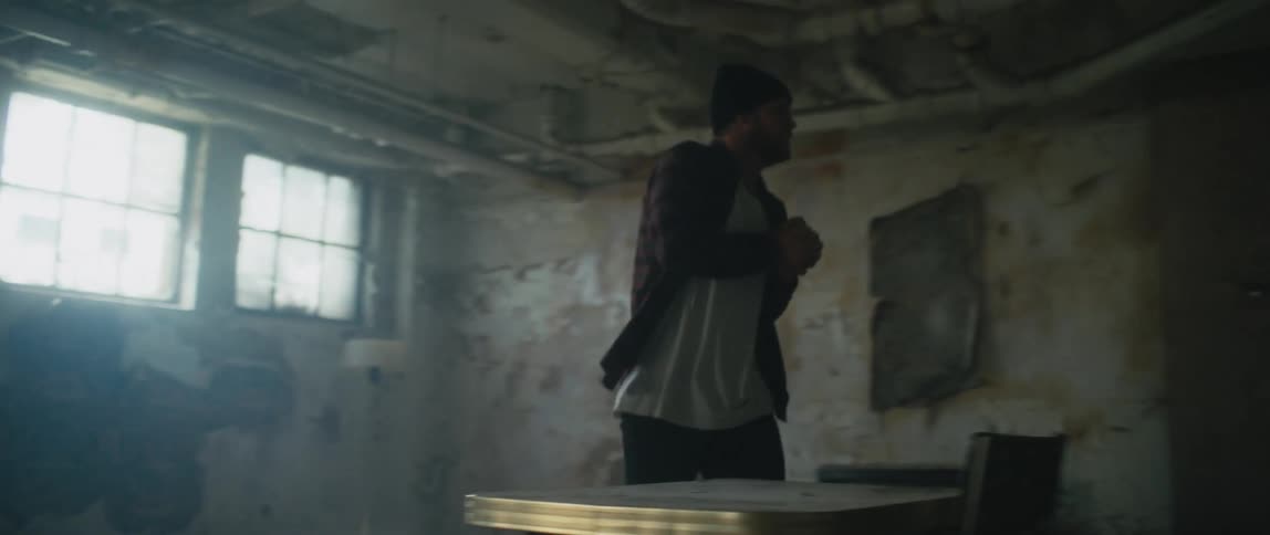 Angry man walks around in a room and knocks over a table and throws a chair against a wall