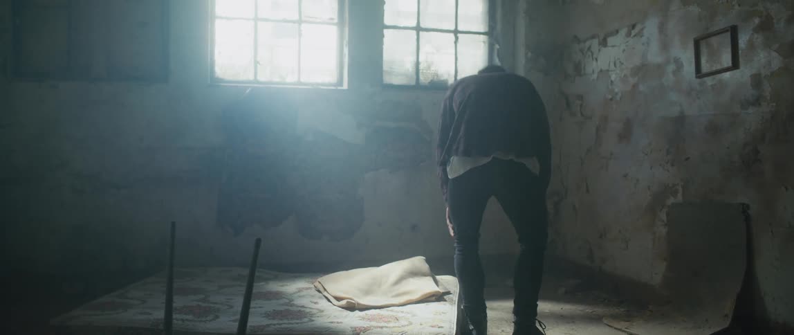 A man sitting down on a mattress in a room