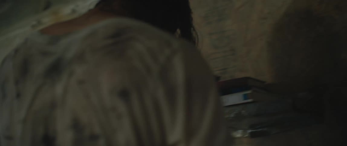 A man grabs a book off a shelf and reads it while walking around a dilapidated apartment