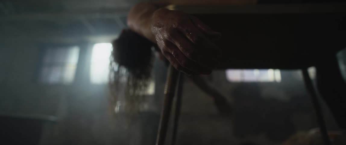 The body of a human lying facedown on a table with their arms hanging over the edge