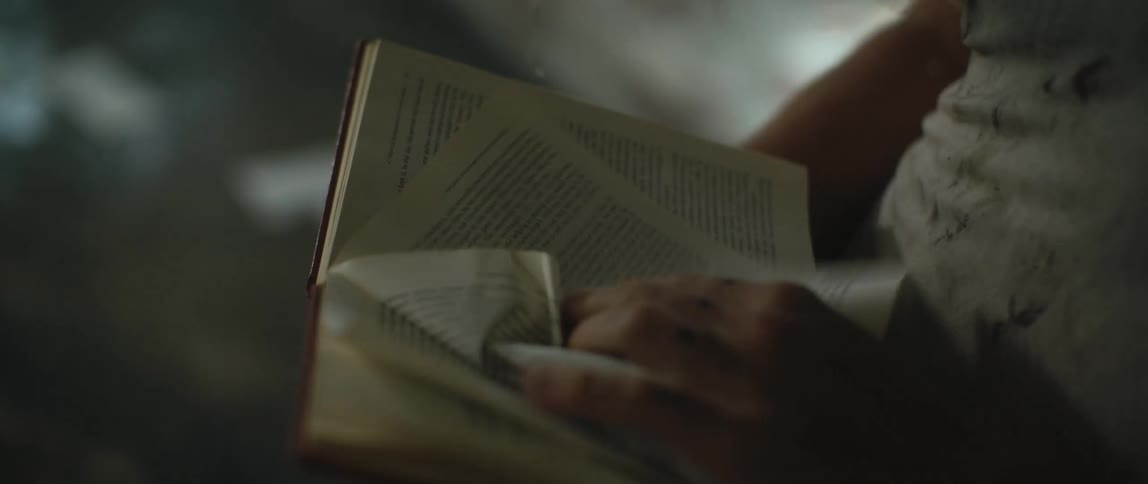 A man holding a book frantically flips the pages tearing one out