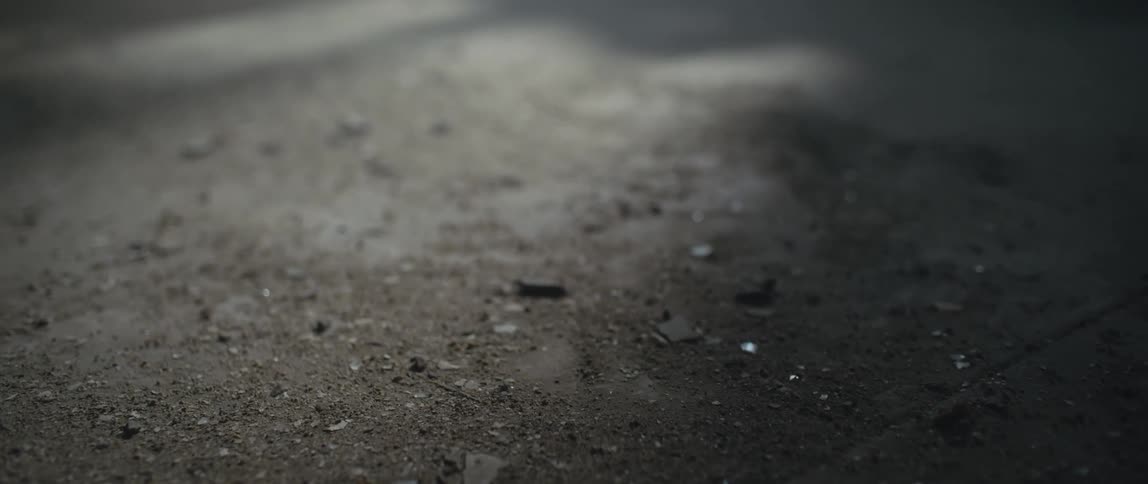 Broken glass and debris cover a cement floor