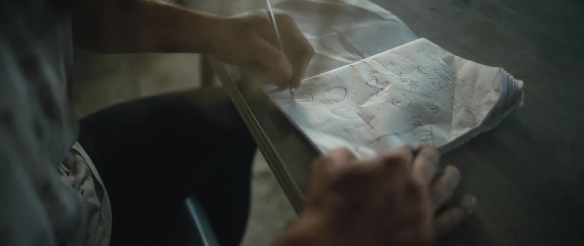 Man writes and draws in notebook pressing hard on the paper