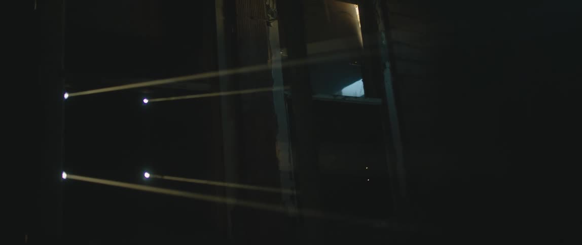 Light is shining through holes in a door in the hallway of a building