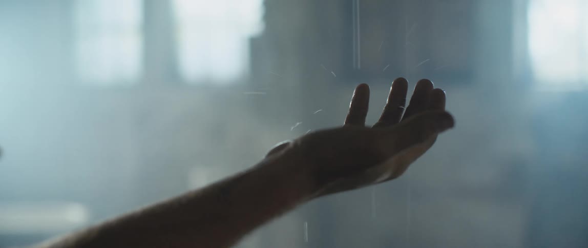 A man touches water dripping from a pipe on the ceiling and lets it run down his arm